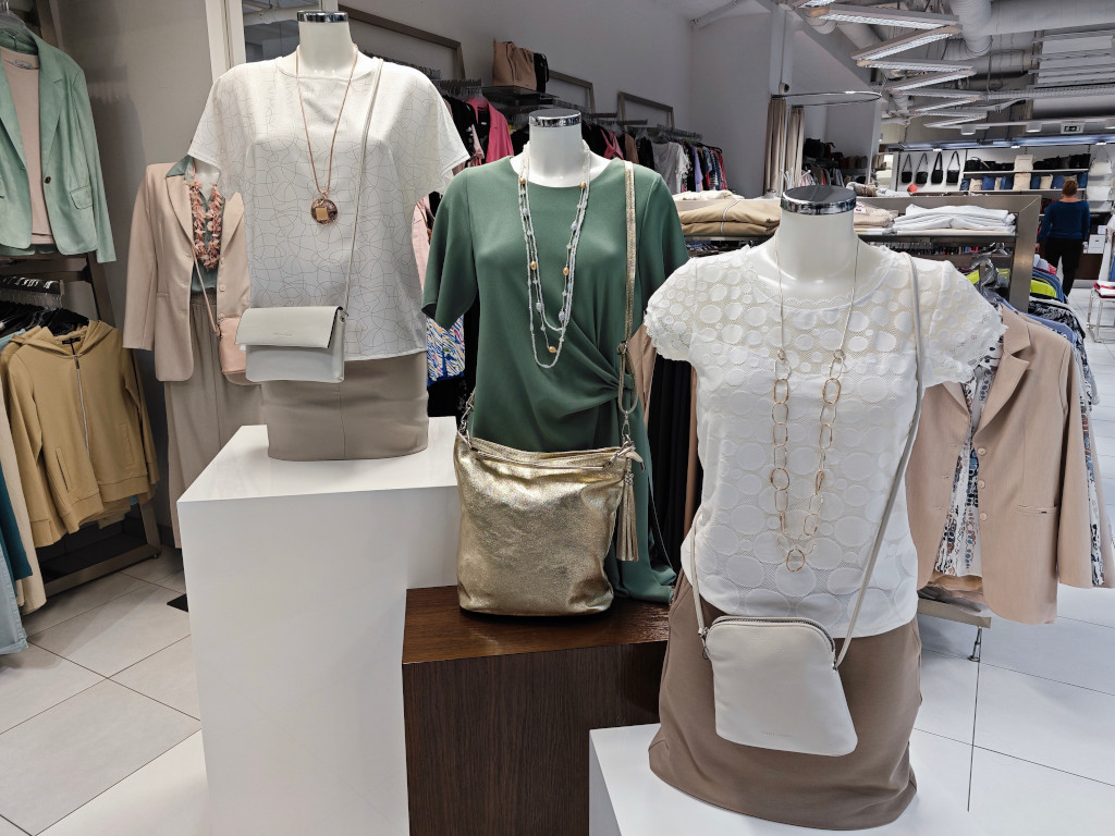 Dámská halenka doplněná o bižuterii a kabelku přes rameno.