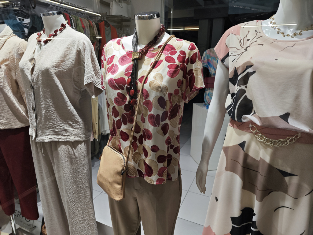 Romanticky laděná vínovo-pudrová dámská halenka s výrazným náhrdelníkem a decentní kabelkou.